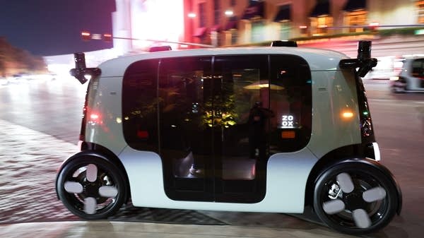 A Zoox taxi drives down a Las Vegas street at night