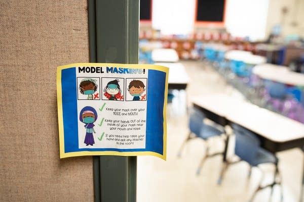 A sign hangs on a doorway to an empty classroom.