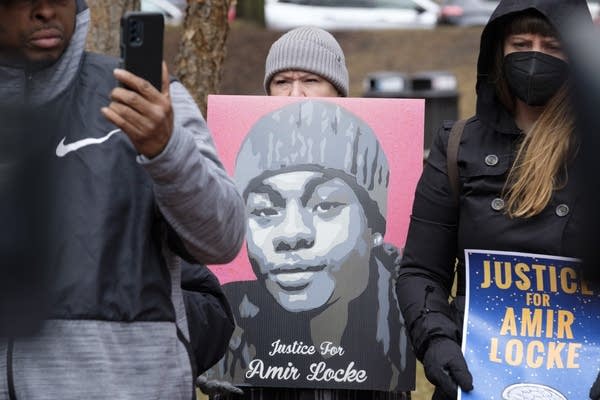 People hold up posters at a protest