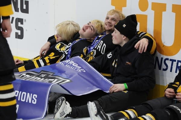 warroad hockey players hold championship banner