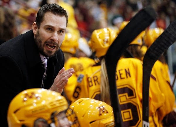 A coach speaks enthusiastically to a hockey team.