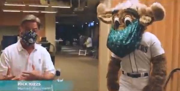 Video still of announcer Rick Rizzs standing next to a masked Mariner Moose