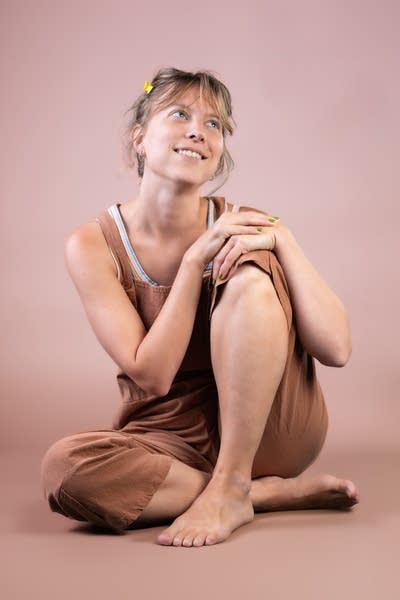 A woman sits on the floor for a studio portrait