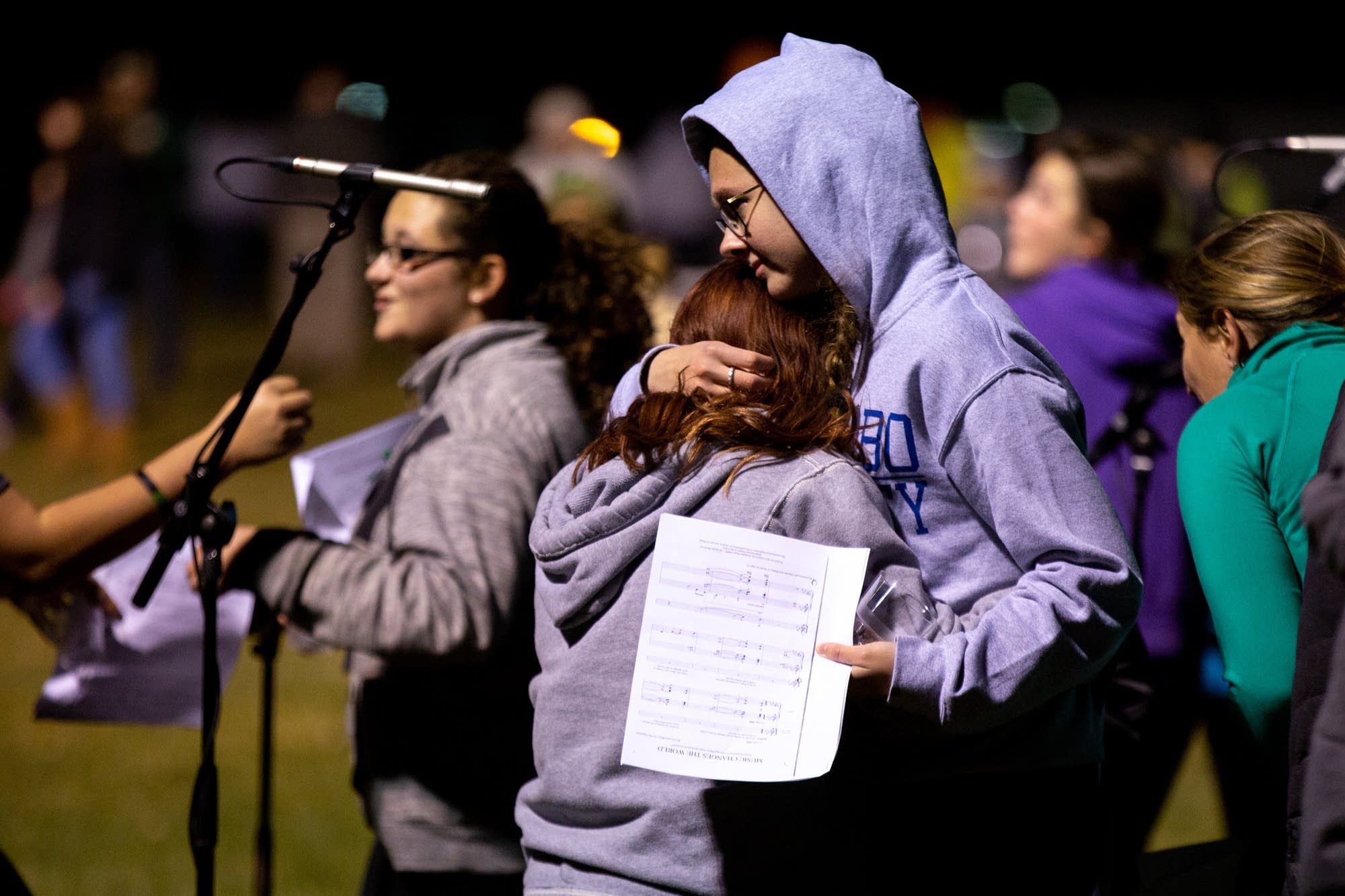 Two students hug after singing at a