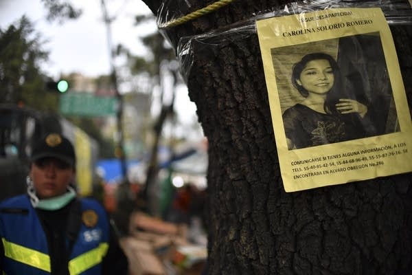 A picture of a missing woman hangs on a tree.