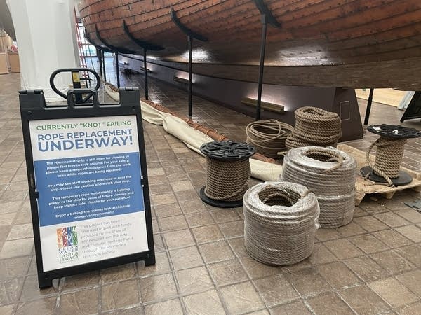 Coils of rope sit on the ground near the ship.
