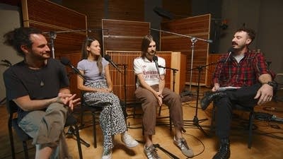 Four people have a conversation in a recording studio
