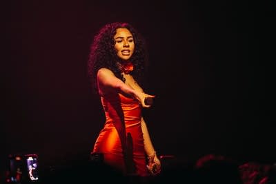 woman on stage holding a mic out to the crowd