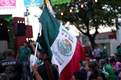 a fan waves a flag at a watch party of Mexico versus England World Cup match 