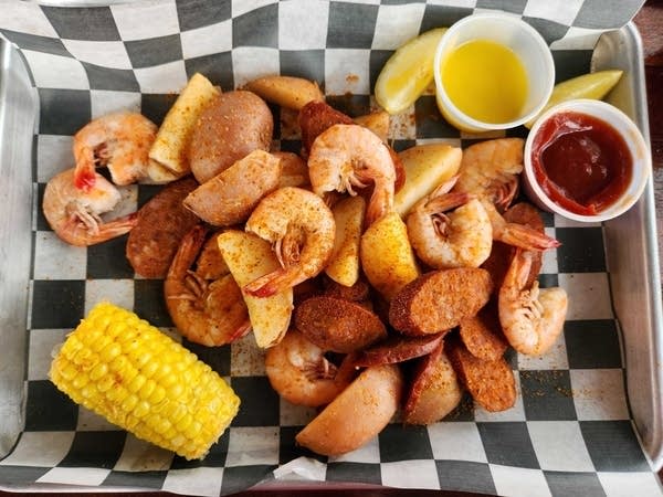 Shrimp, potatoes, sausage and corn in a metal tray.