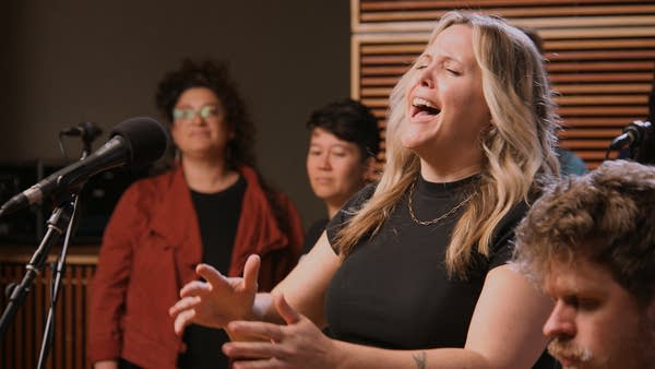 A large group of singers performing in a recording studio