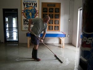 Kyle Collins sweeps water out of the hockey rink.