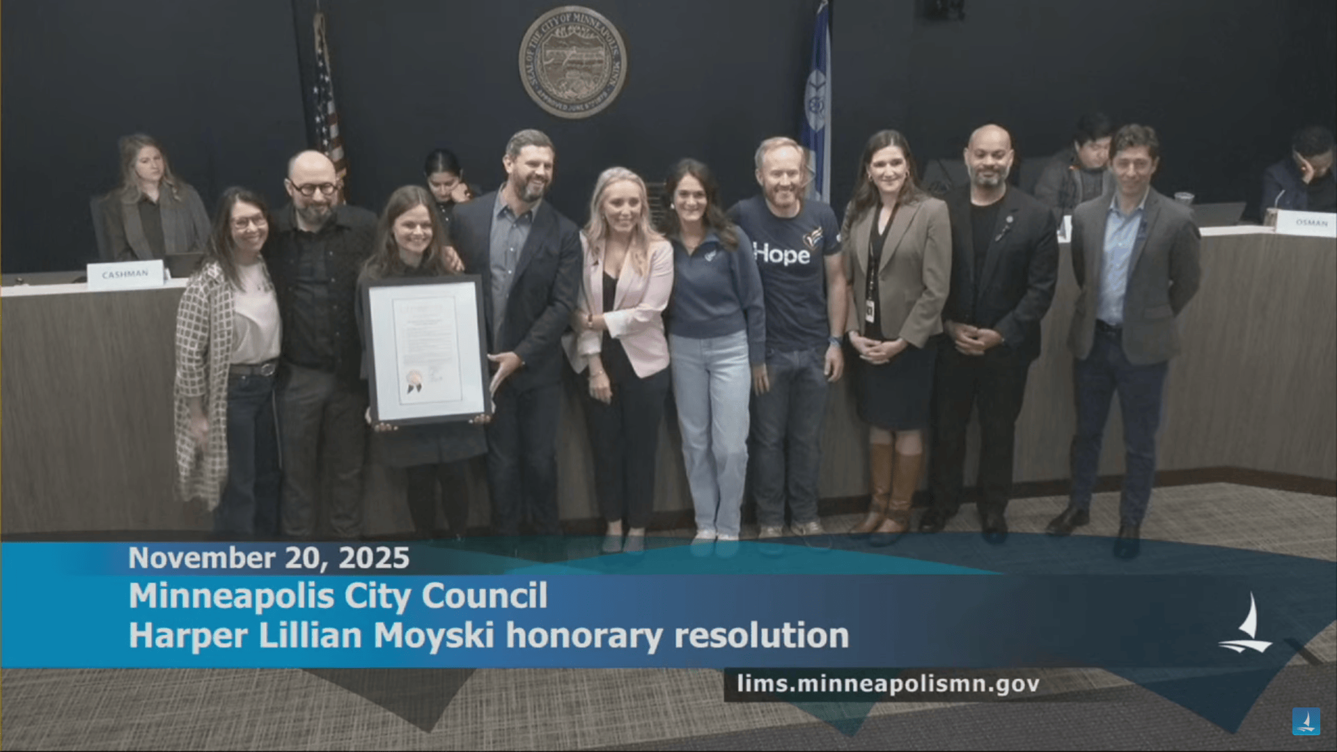 A row of people pose with a framed document