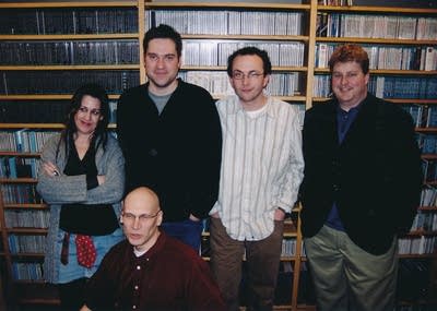 Five people pose for a picture in front of shelves of CDs.