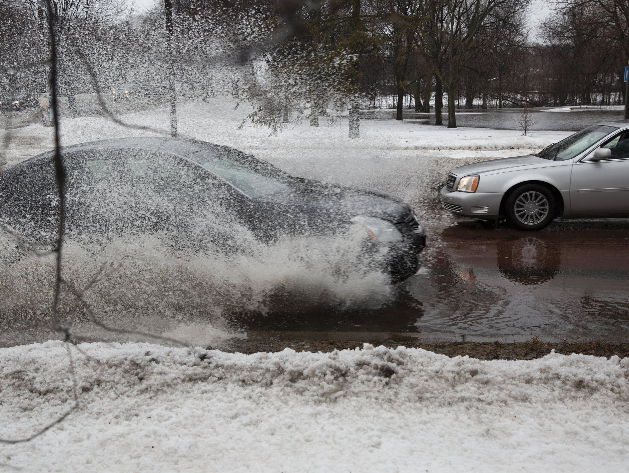 A car drives through water pooled on Minnehaha Parkway and Cedar Avenue