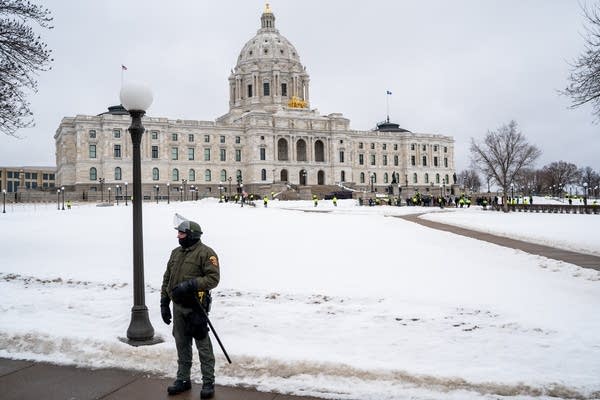 Police in riot gear stand at the capitol.