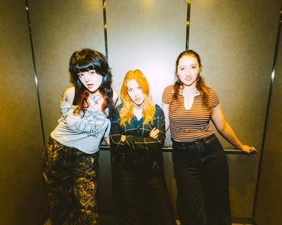 Three musicians stand together for a portrait in an elevator