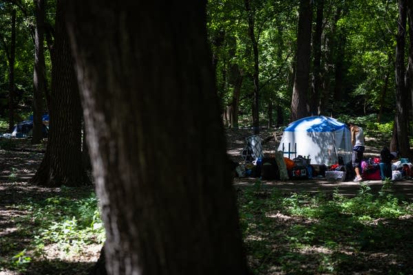A man stands amid his belongings at a campsite