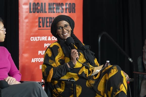 A woman speaks while holding a microphone.