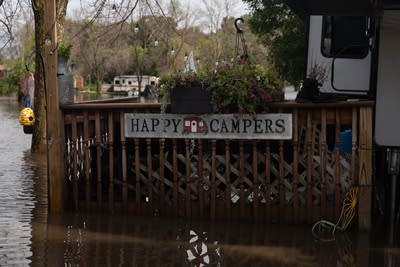 “Happy Campers” sign hangs on a deck outside a recreational vehicle in the campground