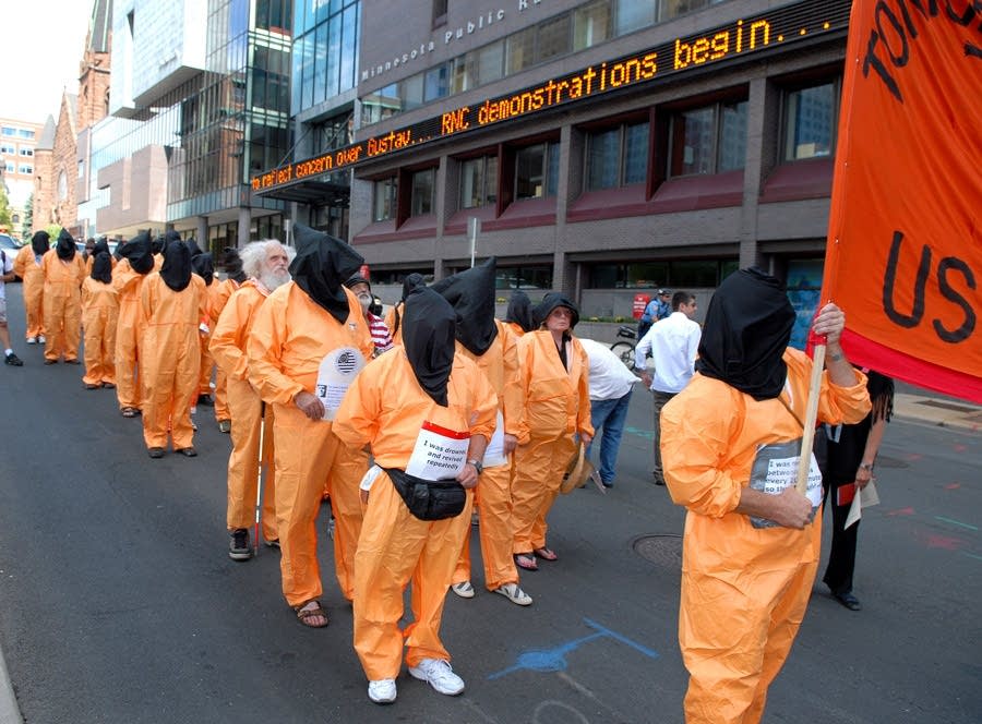 Protesters march in orange jumpsuits