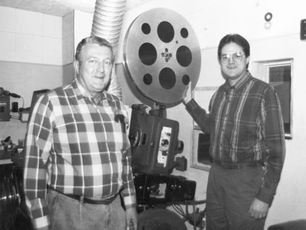two people with a large film reel