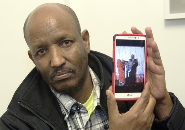 Mahamed Iye shows a photo of his wife and two children.