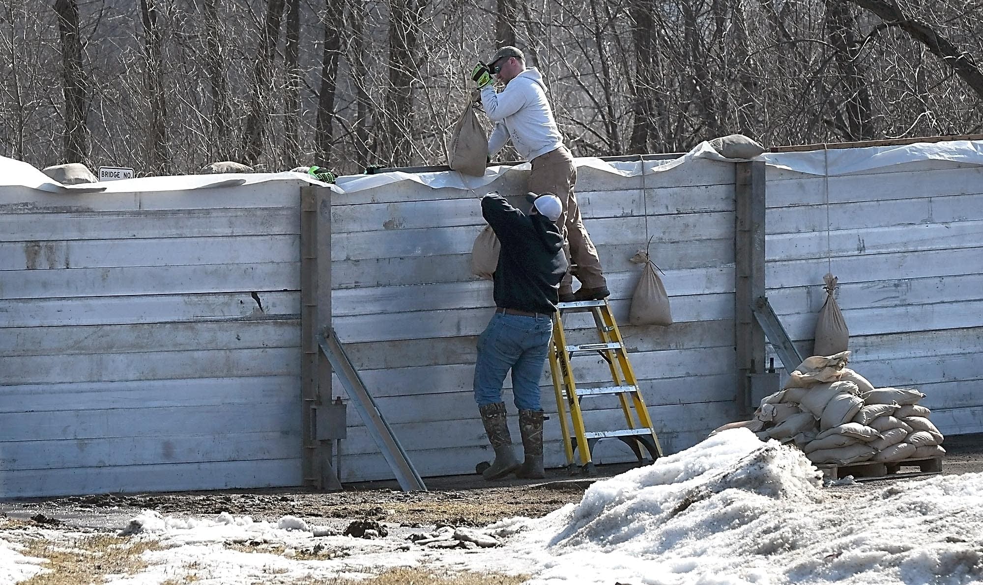 Henderson firefighters work on a flood wall across Highway 19.
