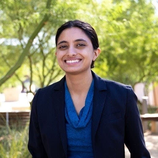 woman in blue and black top smiles