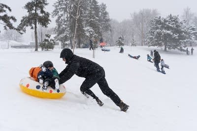 A person pushes a snow tube up a hill