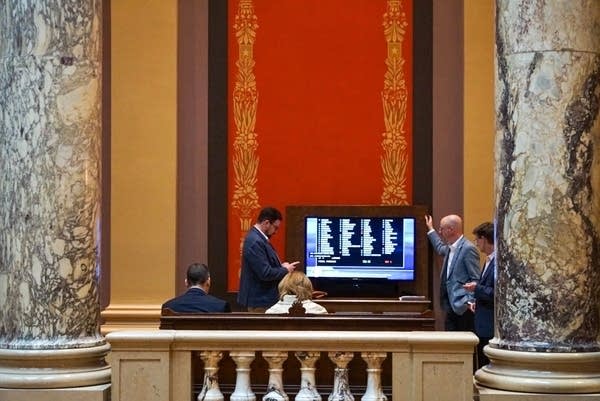People watch a screen to monitor votes at the Legislature.