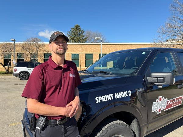 A man in a maroon polo poses next to a black pickup truck.