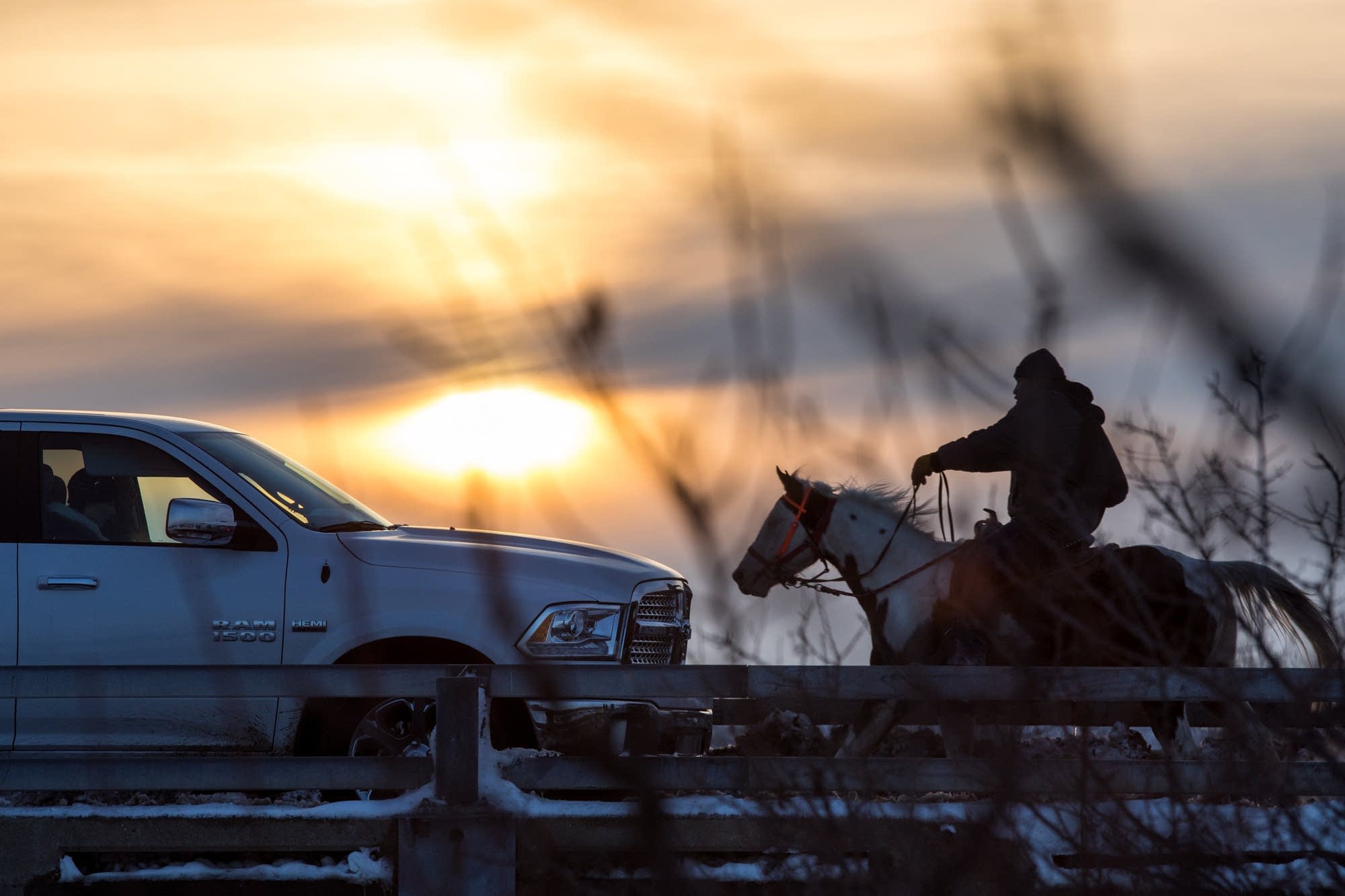 A man rides his horse across a bridge.