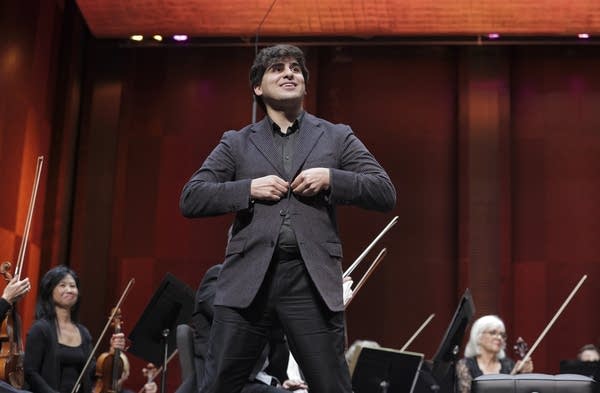 A musician stands up and adjusts his jacket after playing piano