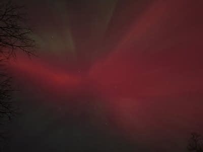 A dark view of green and red lights in the night sky.