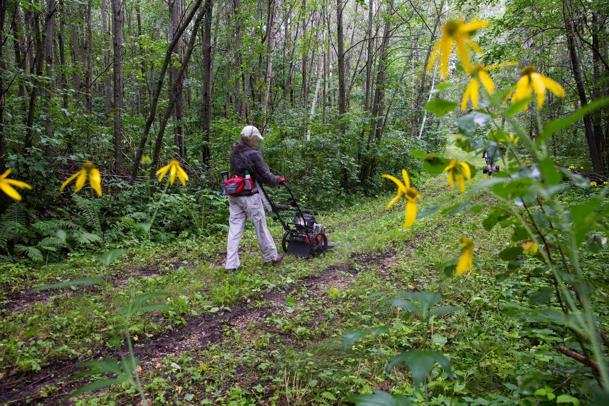 Karen Stenberg pushes a mower down the trail