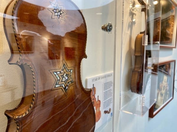 A violin with a Star of David design sits behind a glass case.