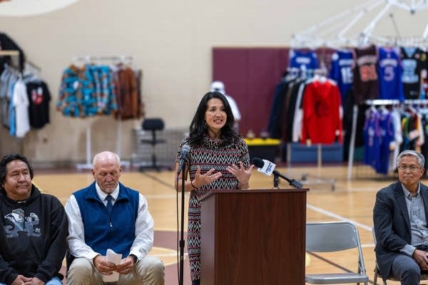 A woman gives a speech in a gymnasium.