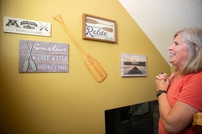 A woman looks at items hanging on a wall and smiles.