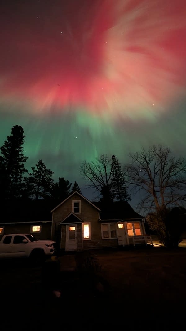 Northern lights are seen in green, red and purple in the night sky.