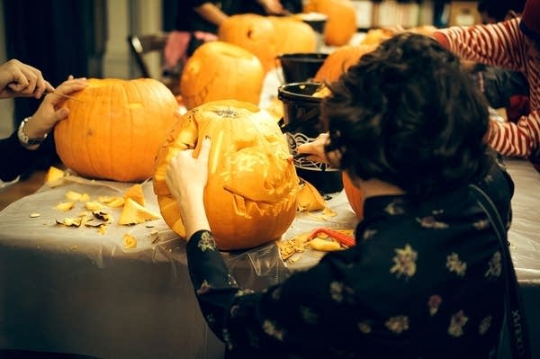 A college student carves a pumpkin at a table full of pumpkins, 2015. 