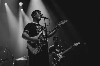 A musician sings and plays guitar in a large music venue
