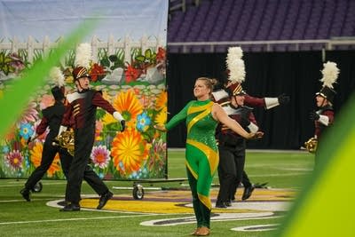 A marching band performs on the field of a football stadium.