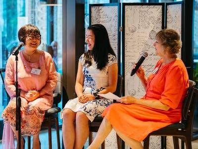 Gao Hong, Ammy Lin, and Julie Amacher sit on stools.
