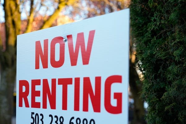 A "Now Renting" sign stands in front of a bush.