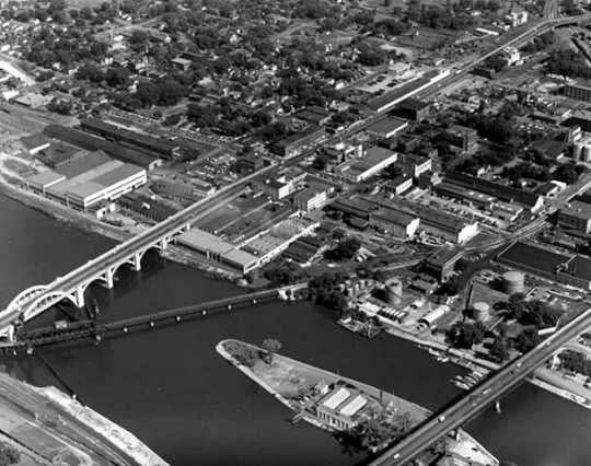 A black and white photo of a community by a river.