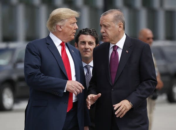 Two men talk while another man looks on