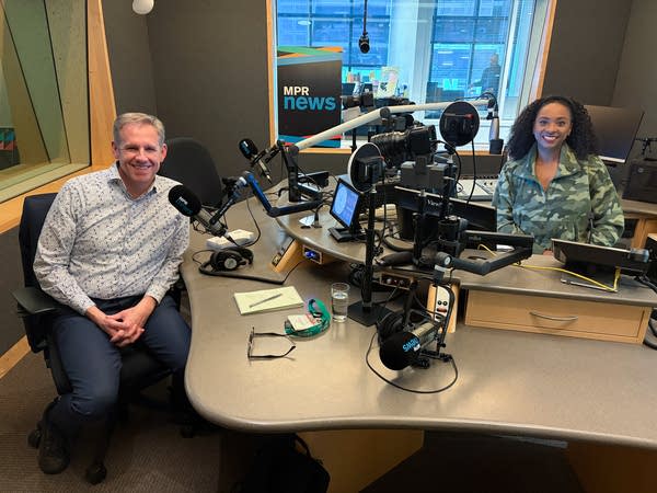 two people smiling in a broadcast studio