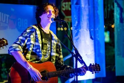 a man singing and playing acoustic guitar on stage