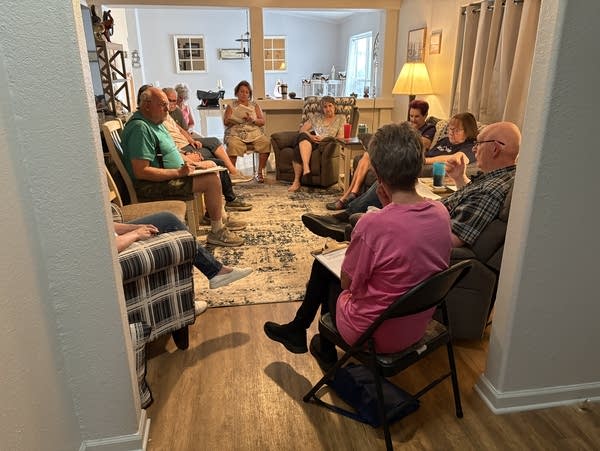A group of people sit together in a living room.